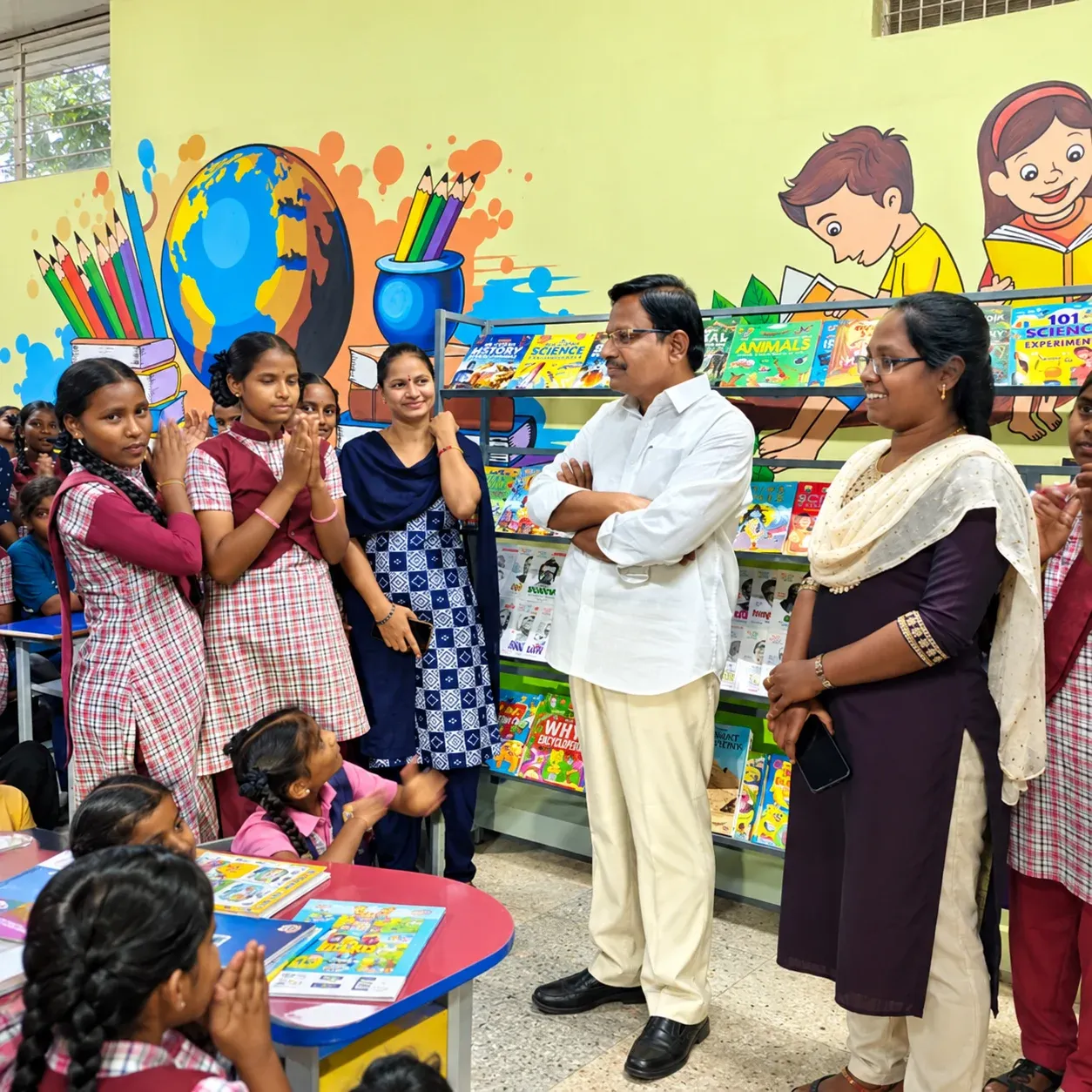 Yennam Srinivas Reddy with girl students and teachers in a brightly painted learning-centre library